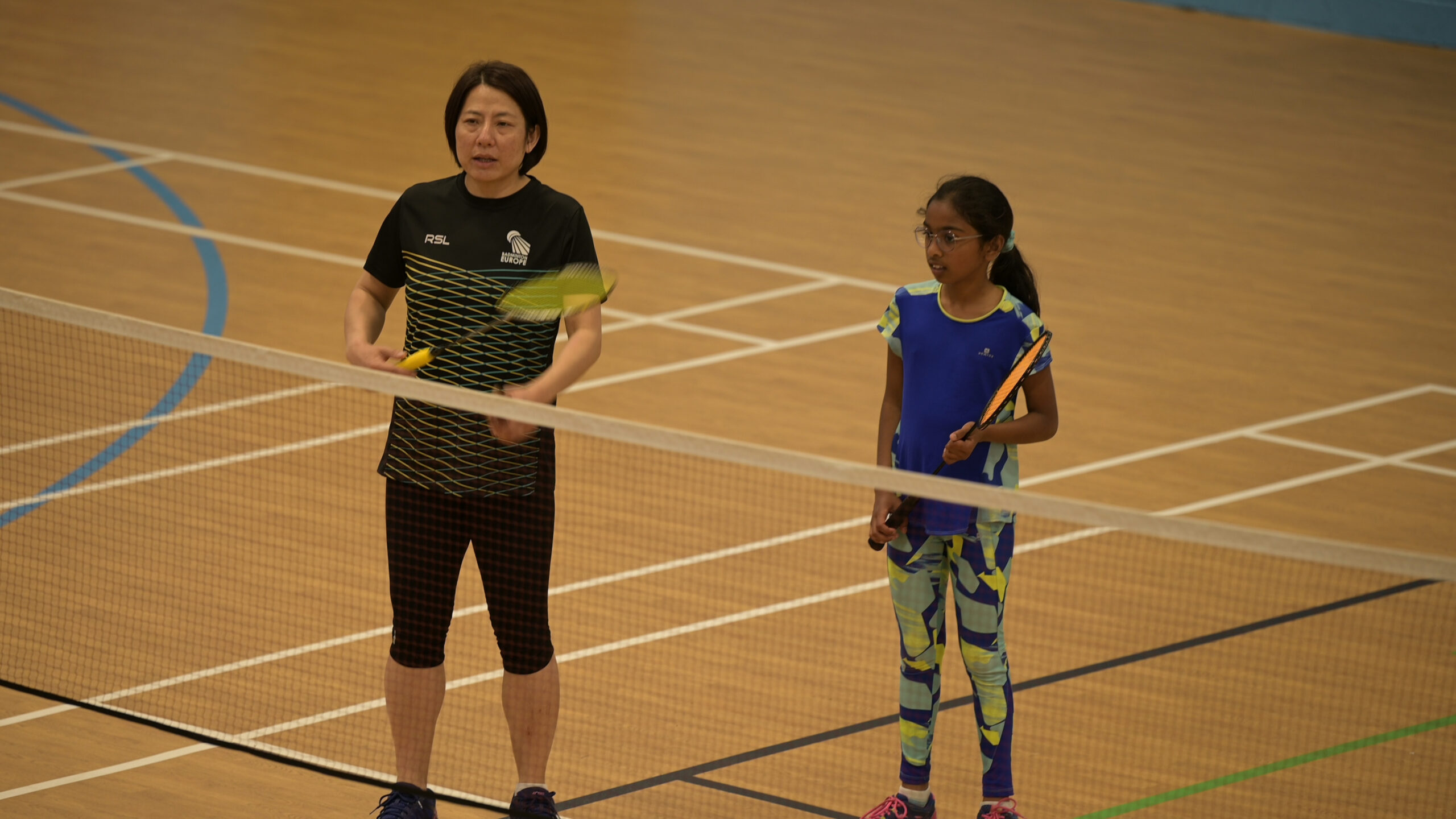 Huaiwen Xu teaching a junior player badminton technique